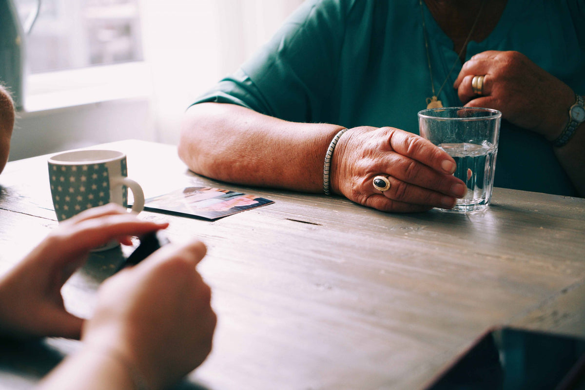 Two individuals sitting at a table with drinks and looking at photos