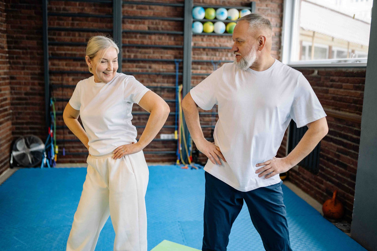 A senior woman and senior man are getting active in a gym.
