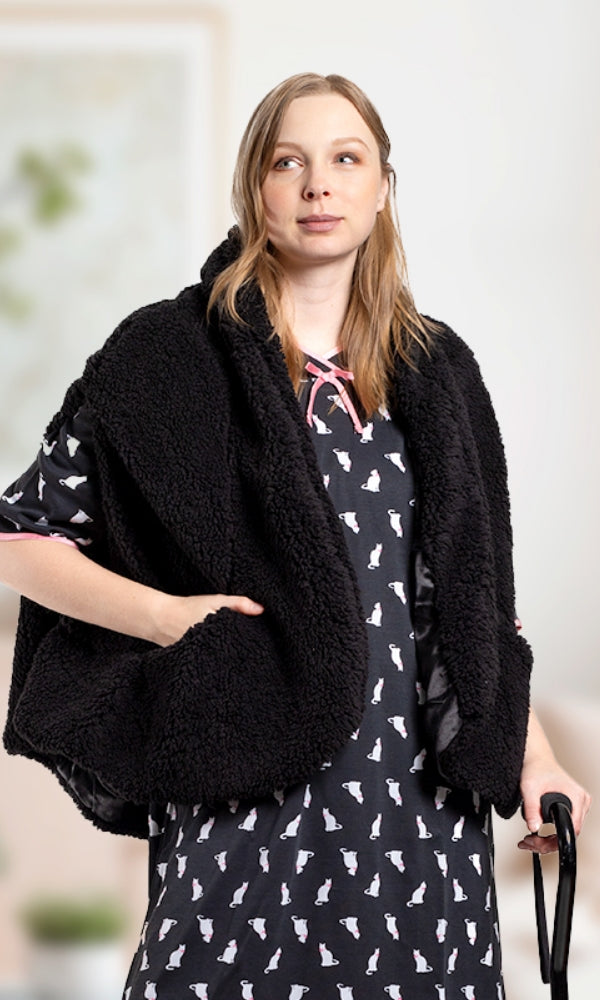 Woman wearing a black fleece wrap over a patterned dress and holding a cane.