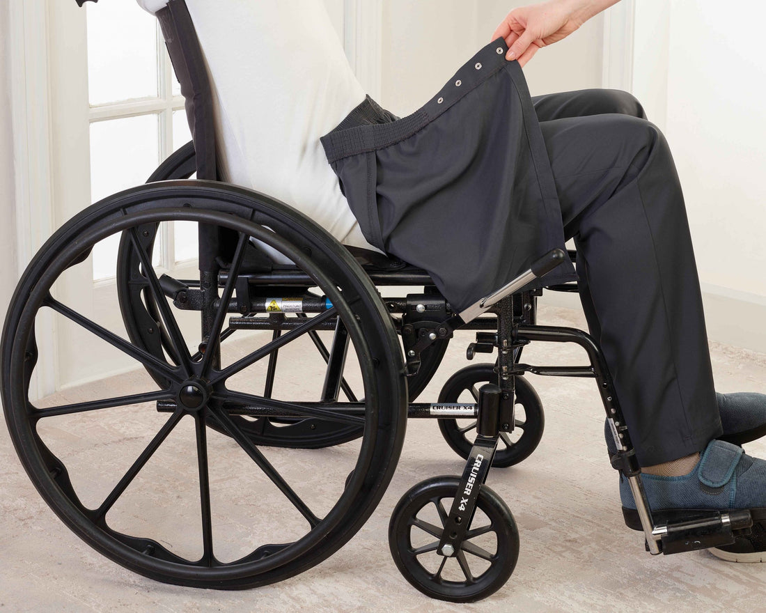 Side view of man seated in wheelchair with open back pants being put on.