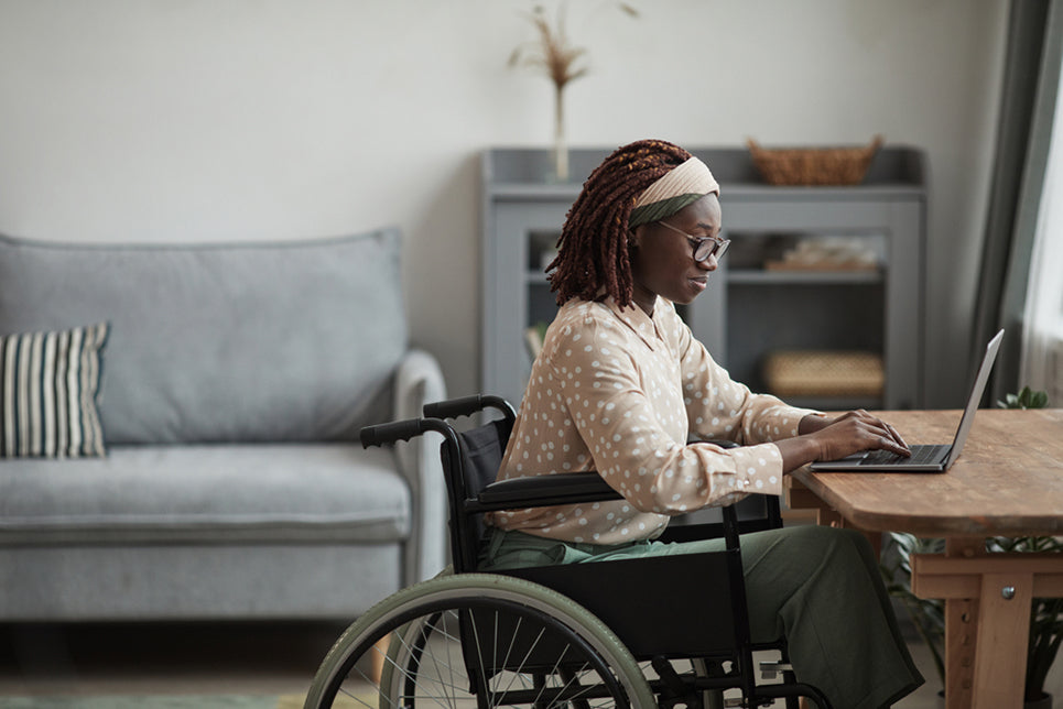 a woman in a wheelchair using a laptop at a desk