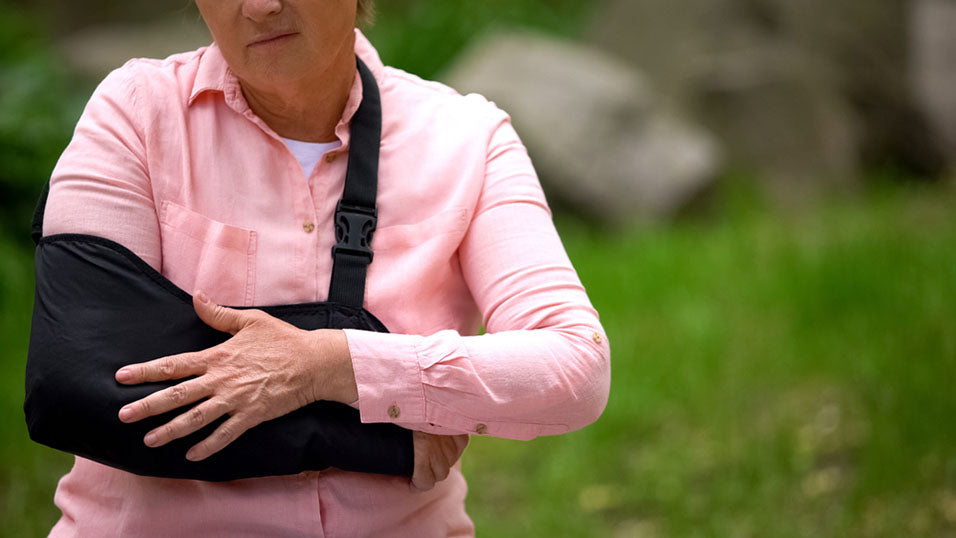 A man using a long handled shoe horn to put on his shoes
