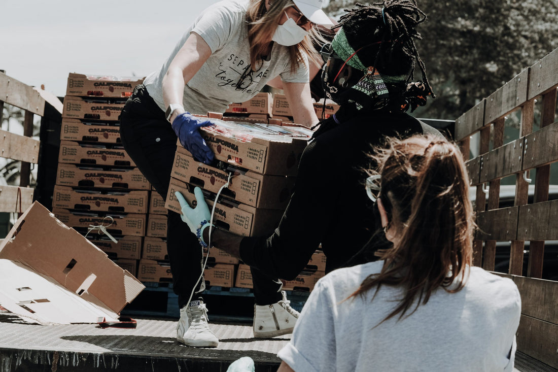 Woman passing boxes of food off a truck to young man.