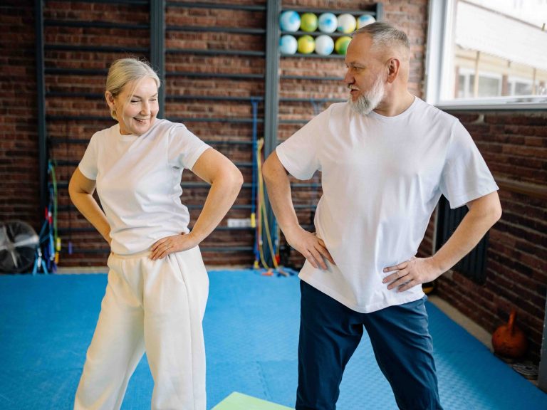 A senior woman and senior man are getting active in a gym.
